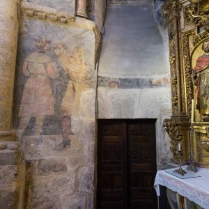 Puerta de la sacristía de madera tallada entre pinturas murales renacentistas y retablo barroco en la Capilla de San Pedro.