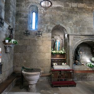 Baptisterio de la Iglesia de la Corticela en Santiago de Compostela. Pila bautismal de piedra y relieves de la Oración en el Huerto. Estilo románico.
