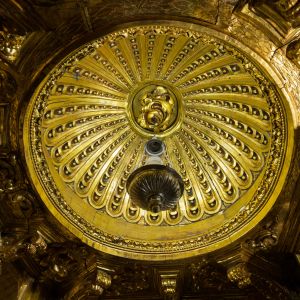 Capulín dorado sobre el camarín del Apóstol Santiago. Cúpula barroca con nervios tallados y lámpara de plata en la Capilla Mayor de la Catedral.