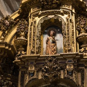 Detalle de San Juan Evangelista en el remate del retablo barroco de la Capilla de San Juan, Catedral de Santiago de Compostela. Arte sacro dorado.