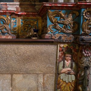 Detalle tallado y policromado zócalo del retablo de la Capilla de Mondragón con motivos dorados y figura femenina fantástica.