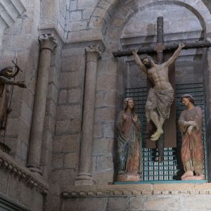 Calvario gótico en piedra con Cristo, María y San Juan y escultura moderna de San Juan Bautista en bronce.