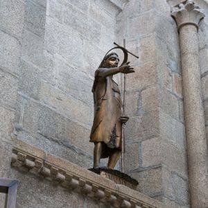Escultura moderna de San Juan Bautista junto a un calvario gótico en el transepto sur del baptisterio.