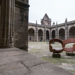 Vista del patio del claustro con escultura de acero corten conmemorativa del 800 aniversario de la consagración en primer plano y la Torre de la Vela 