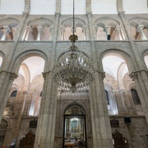 Alzado románico de la Catedral de Santiago con arcos peraltados, triforio y gran lámpara de cristal.