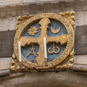Detalle de la Cruz de Consagración de 1211 sobre la Puerta Santa. Medallón románico policromado en oro y azul con símbolos del Alfa y la Omega, sol y 