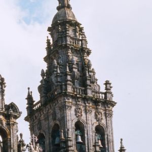 Detalle del cuerpo de campanas de la torre sur de la Catedral de Santiago, con sus arcos de piedra y remates barrocos contra un cielo claro.