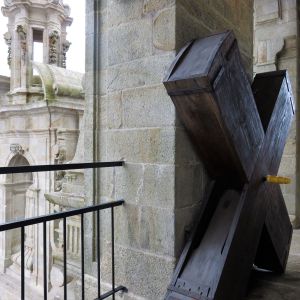Gran carraca de madera oscura en forma de aspa apoyada en el interior de la torre de la Catedral de Santiago, con vistas a los pináculos de piedra.