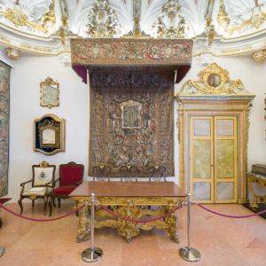 Mesa presidencial bajo dosel de Carlos III, sillón de Juan Pablo II y caja de votaciones en la Sala Capitular del Museo de la Catedral de Santiago.