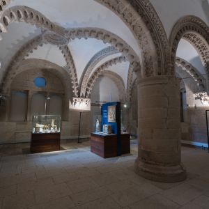 Sala Sinodal del Palacio de Gelmírez con arcos románicos de billetes y exposición del Museo de la Catedral de Santiago de Compostela