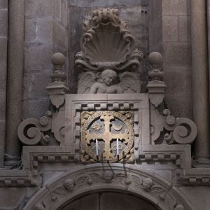 Cruz de consagración de 1211 sobre la portada de la cripta del Pórtico de la Gloria, con decoración barroca de Simón Rodríguez. Catedral de Santiago.