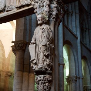 Santiago Apóstol en el parteluz del Pórtico de la Gloria con báculo en tau, nimbo de bronce y capitel de la Santísima Trinidad.